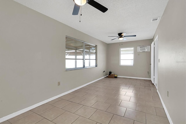 tiled empty room with ceiling fan, a wall mounted AC, and a textured ceiling