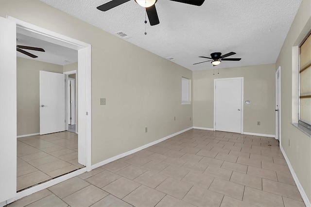 unfurnished room with a textured ceiling, ceiling fan, and light tile patterned flooring