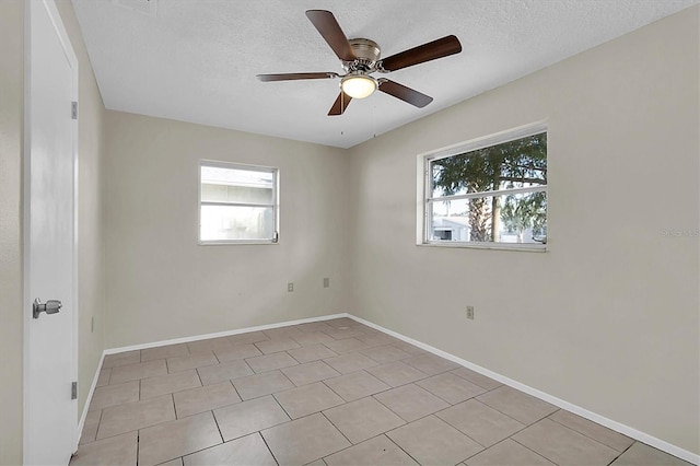 spare room featuring a textured ceiling, light tile patterned floors, and ceiling fan