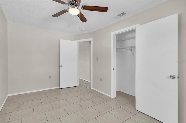 unfurnished bedroom featuring a closet, a textured ceiling, light tile patterned floors, and ceiling fan