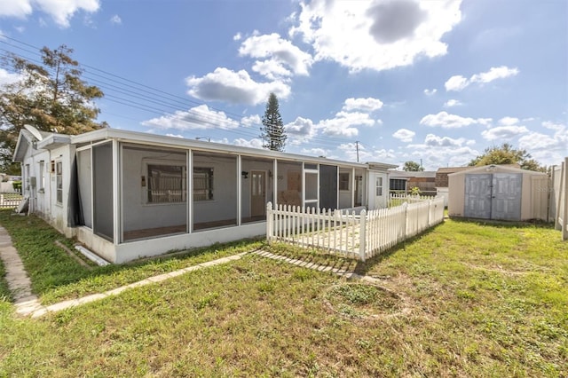 back of house featuring a storage shed, a sunroom, and a yard