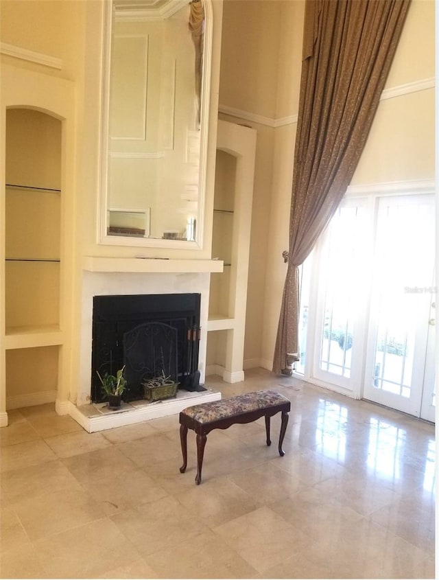 sitting room featuring crown molding, built in features, and a towering ceiling