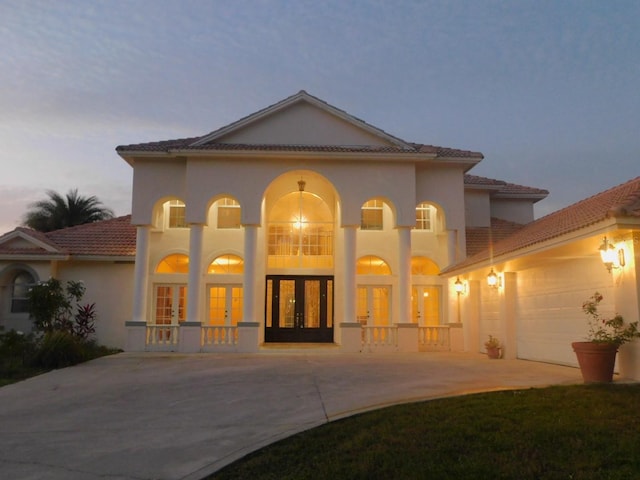 back house at dusk with french doors and a garage