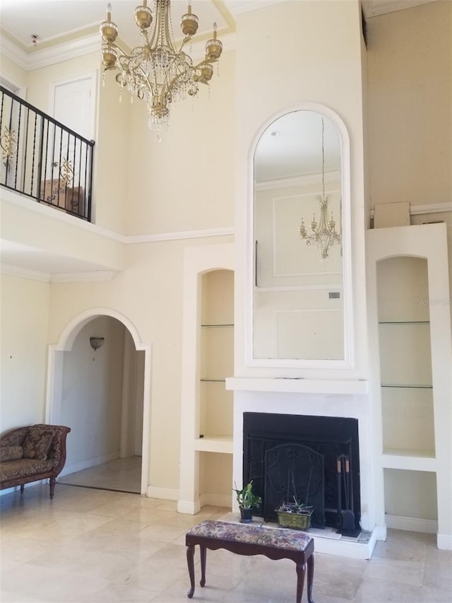 living room with built in shelves, an inviting chandelier, a high ceiling, and ornamental molding