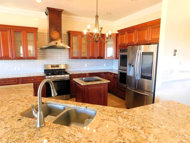 kitchen featuring light stone countertops, sink, stainless steel appliances, wall chimney range hood, and pendant lighting