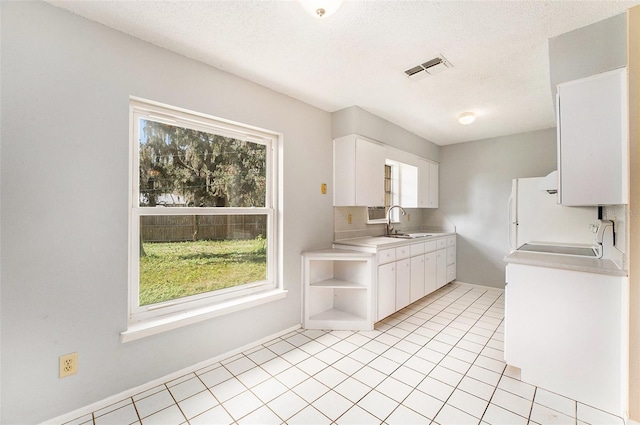 kitchen featuring white cabinetry, a textured ceiling, sink, and light tile patterned floors