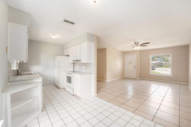 kitchen with electric stove, light tile patterned floors, sink, ceiling fan, and white cabinetry