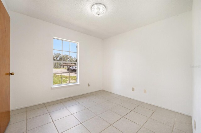 tiled spare room featuring a textured ceiling