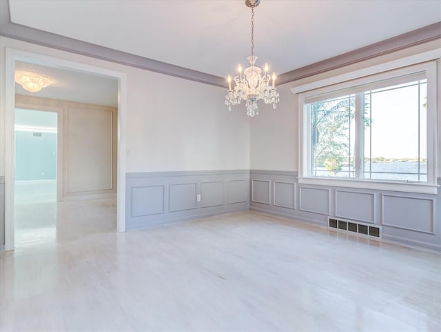 spare room featuring crown molding and an inviting chandelier