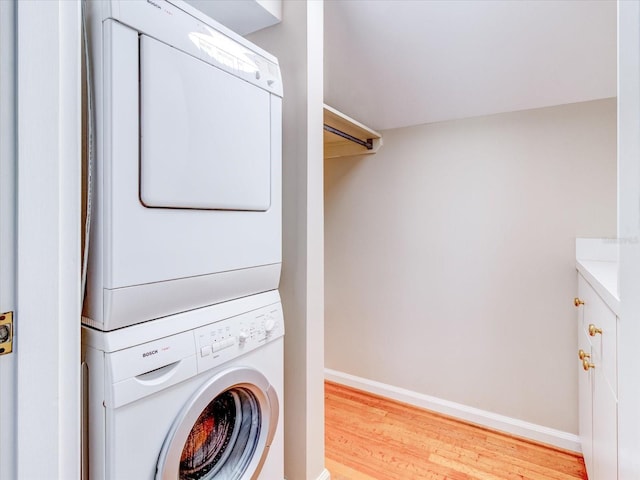 laundry area featuring stacked washer and clothes dryer and light wood-type flooring