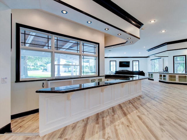 kitchen featuring a breakfast bar, dark stone countertops, white cabinetry, and light hardwood / wood-style flooring