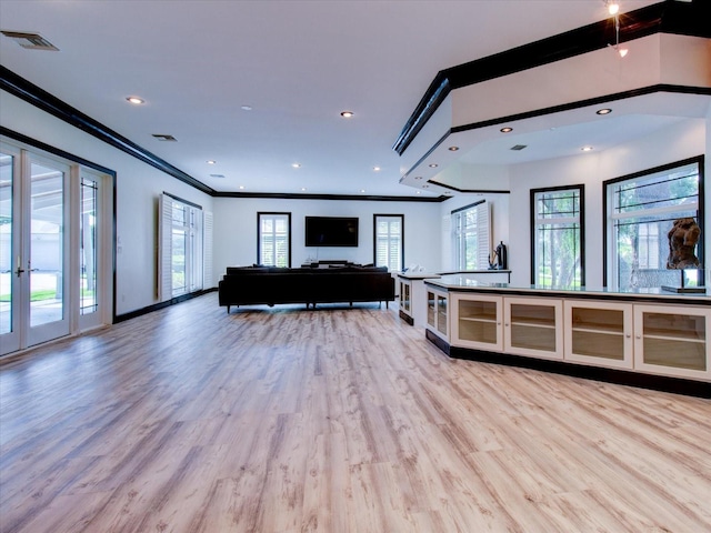 unfurnished living room featuring a healthy amount of sunlight, light hardwood / wood-style floors, and ornamental molding