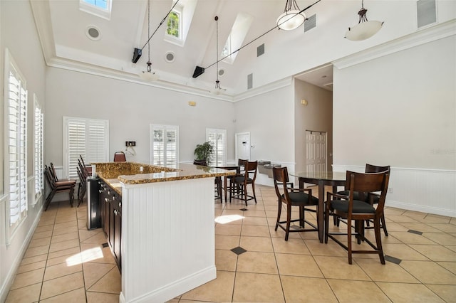 kitchen with a skylight, light tile patterned floors, a towering ceiling, a wealth of natural light, and decorative light fixtures