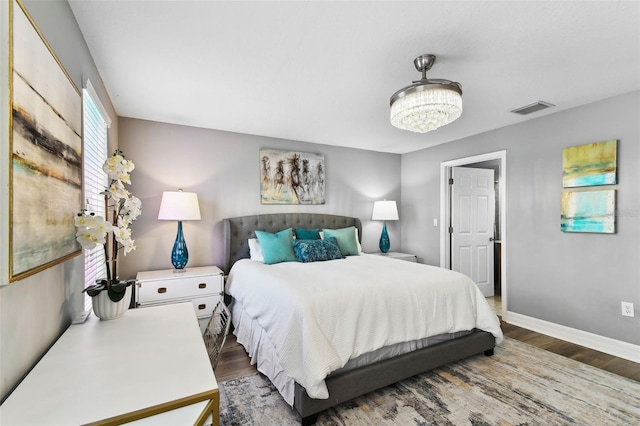 bedroom with dark wood-type flooring and a notable chandelier