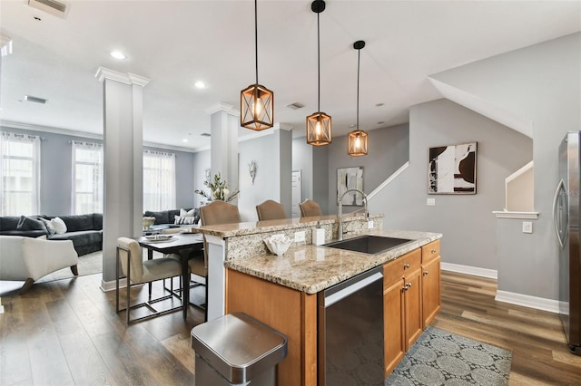 kitchen with a breakfast bar, sink, an island with sink, appliances with stainless steel finishes, and decorative light fixtures