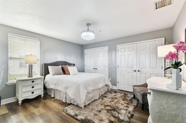 bedroom featuring dark hardwood / wood-style floors and multiple closets