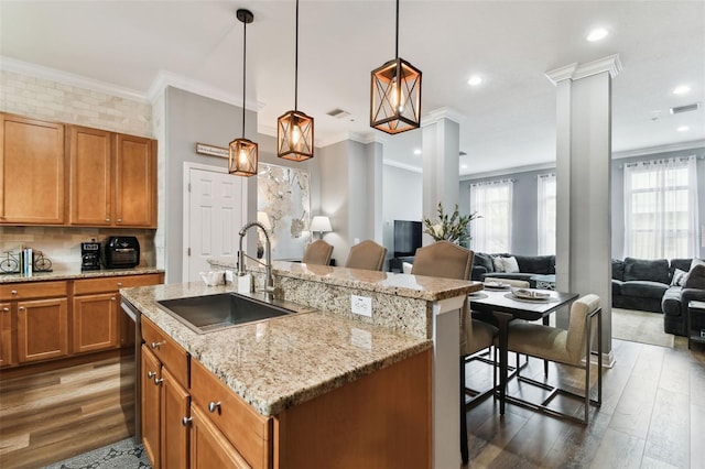 kitchen with a breakfast bar area, ornate columns, sink, and a center island with sink