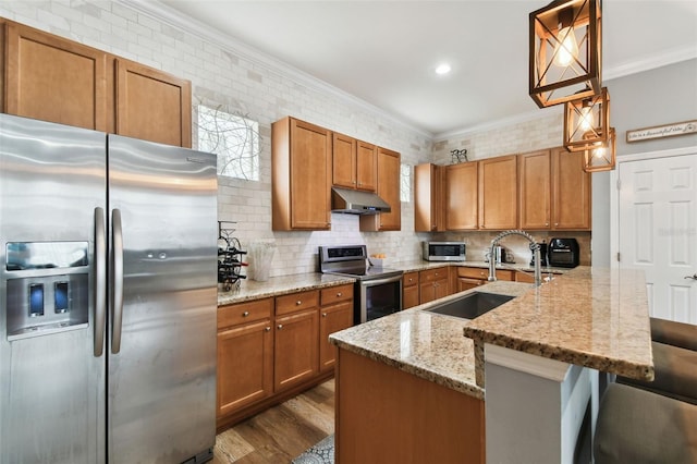 kitchen featuring a kitchen bar, appliances with stainless steel finishes, ornamental molding, sink, and pendant lighting