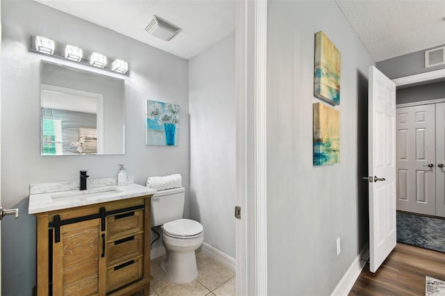 bathroom with tile patterned floors, vanity, toilet, and a textured ceiling