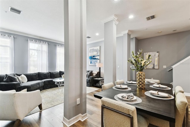 dining space featuring decorative columns, light hardwood / wood-style flooring, plenty of natural light, and ornamental molding