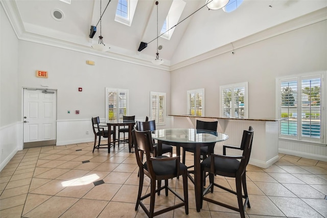 dining area featuring a skylight, crown molding, a towering ceiling, and light tile patterned floors