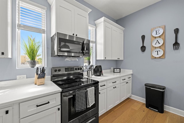 kitchen with white cabinets, light hardwood / wood-style floors, and appliances with stainless steel finishes