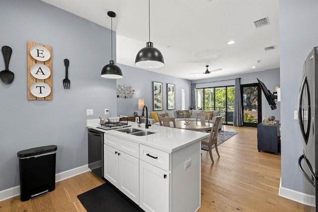 kitchen with decorative light fixtures, black dishwasher, sink, white cabinets, and light hardwood / wood-style flooring