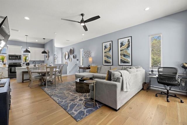 living room featuring sink, ceiling fan, and light hardwood / wood-style flooring