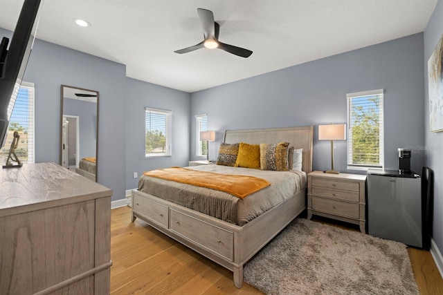 bedroom with ceiling fan, multiple windows, and light wood-type flooring