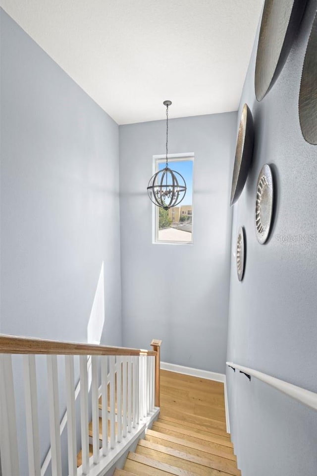 staircase featuring hardwood / wood-style floors and a notable chandelier