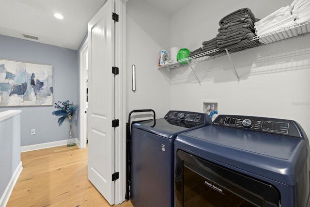 washroom with separate washer and dryer and light hardwood / wood-style flooring