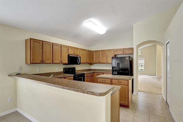 kitchen with a peninsula, black appliances, arched walkways, and vaulted ceiling