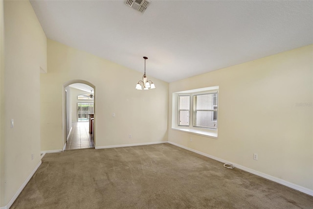 carpeted empty room with a wealth of natural light, ceiling fan with notable chandelier, and lofted ceiling