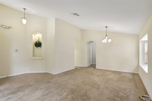 unfurnished room with high vaulted ceiling, an inviting chandelier, and light carpet