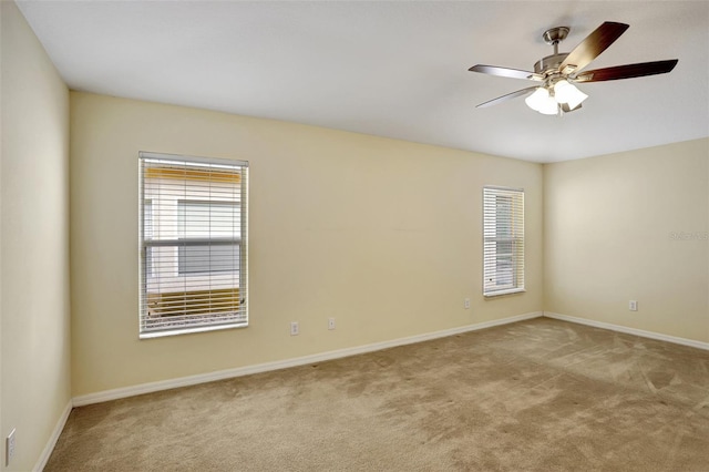 empty room with ceiling fan, plenty of natural light, baseboards, and light colored carpet