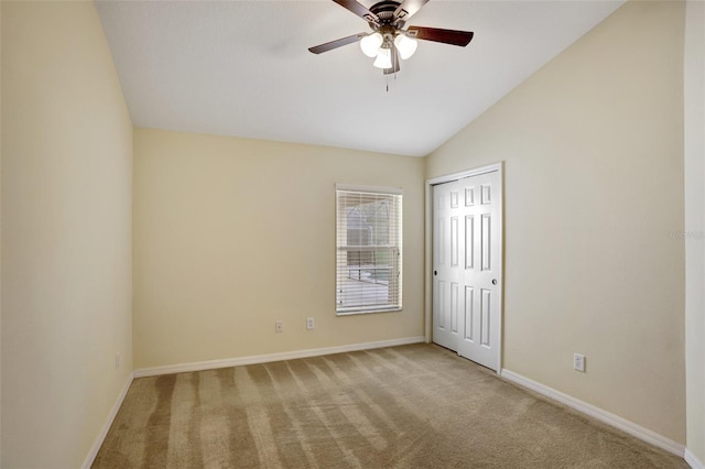 spare room with baseboards, vaulted ceiling, a ceiling fan, and light colored carpet