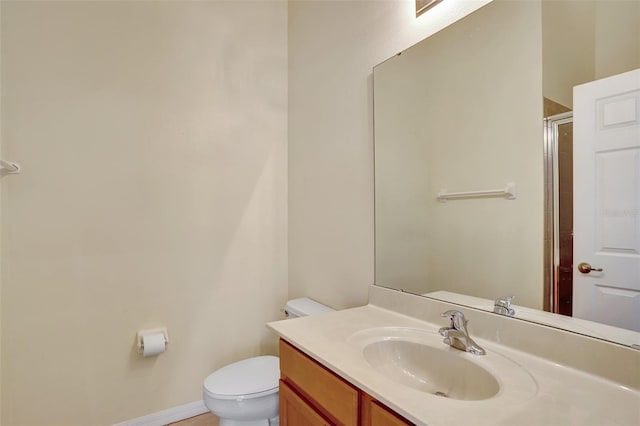 full bathroom with toilet, a shower with shower door, baseboards, and vanity