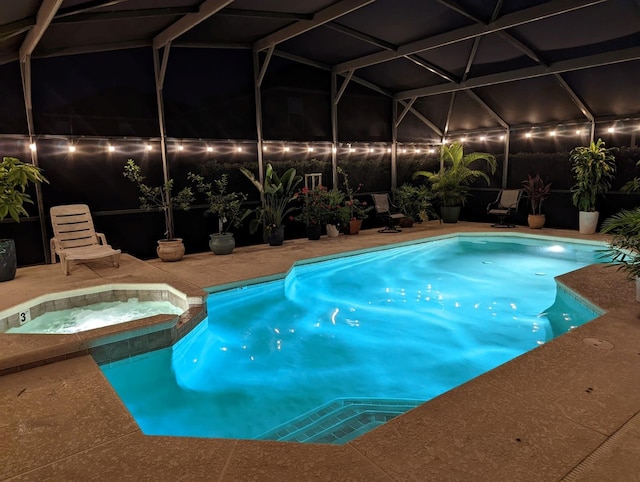 pool at twilight with glass enclosure, a patio, and a pool with connected hot tub