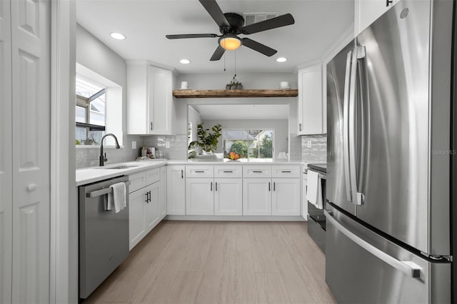 kitchen with white cabinets, stainless steel appliances, sink, and tasteful backsplash