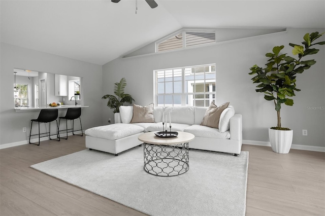 living room with ceiling fan, plenty of natural light, light wood-type flooring, and lofted ceiling