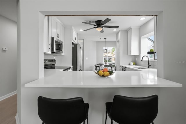 kitchen with white cabinets, kitchen peninsula, appliances with stainless steel finishes, and sink