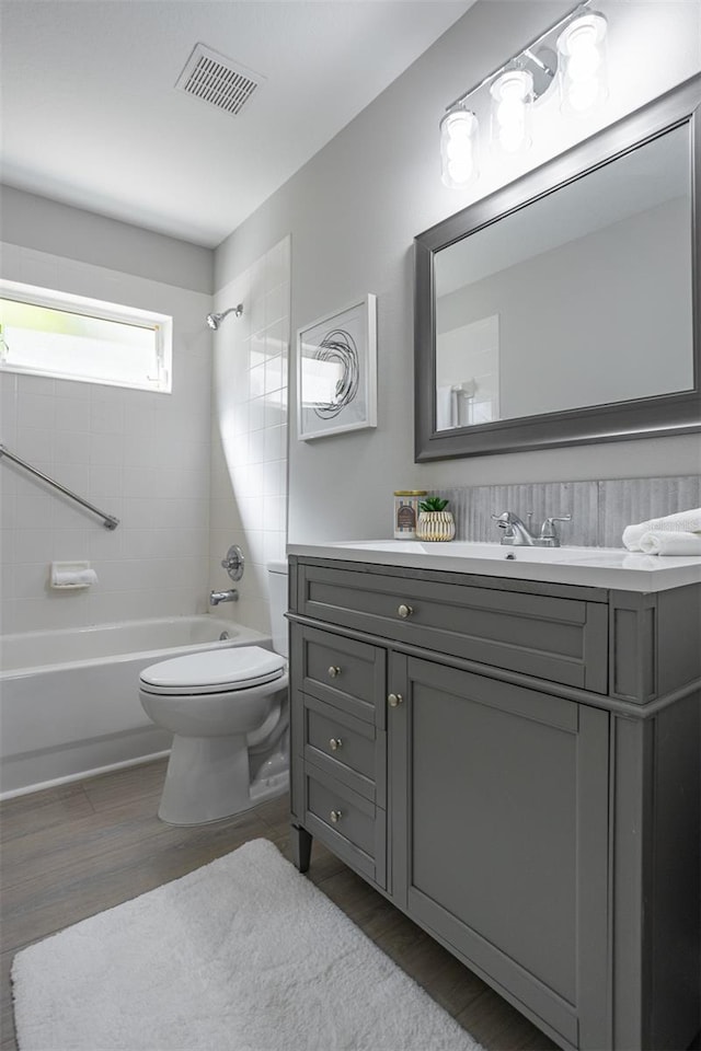 full bathroom featuring toilet, tiled shower / bath combo, vanity, and hardwood / wood-style flooring