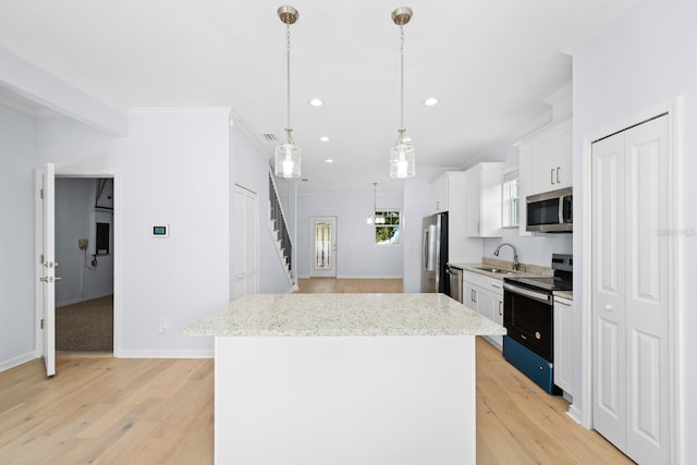 kitchen featuring white cabinets, sink, hanging light fixtures, a kitchen island, and stainless steel appliances