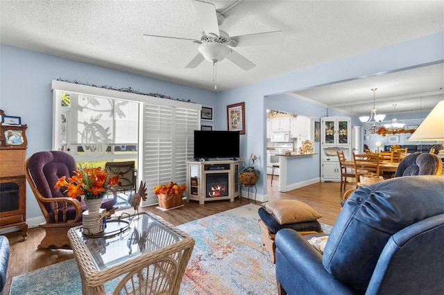 living room with a textured ceiling, ceiling fan with notable chandelier, and wood-type flooring