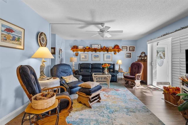 living room featuring dark wood-type flooring, ceiling fan, and a textured ceiling