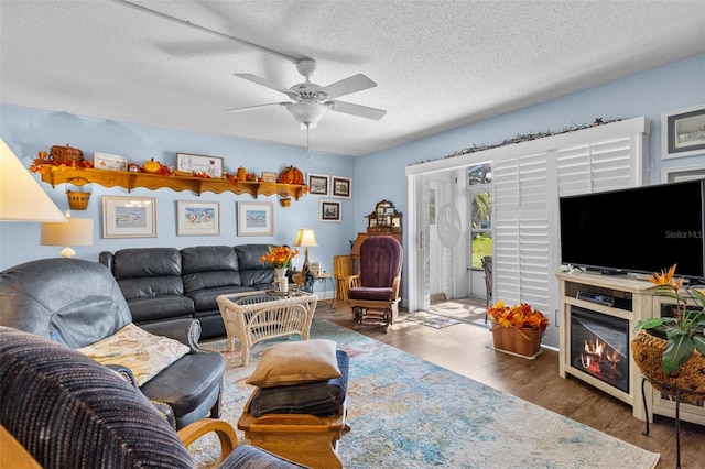 living room featuring ceiling fan, a textured ceiling, and dark hardwood / wood-style flooring