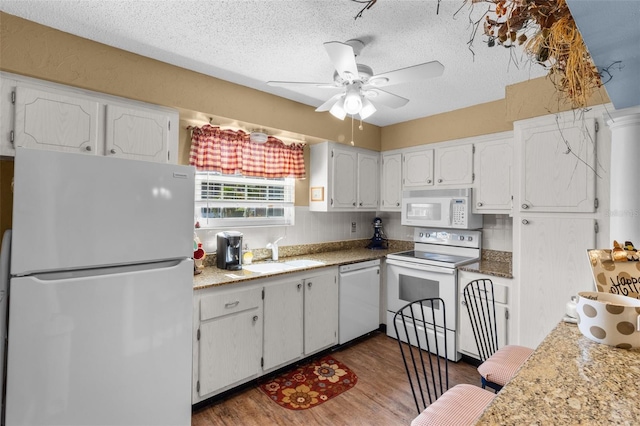 kitchen featuring white cabinetry, dark hardwood / wood-style flooring, sink, white appliances, and ceiling fan