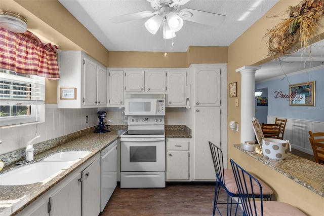 kitchen featuring white cabinetry, light stone countertops, white appliances, ornate columns, and dark hardwood / wood-style flooring