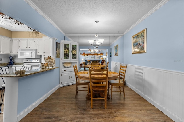 dining space featuring dark hardwood / wood-style flooring, a textured ceiling, crown molding, and an inviting chandelier