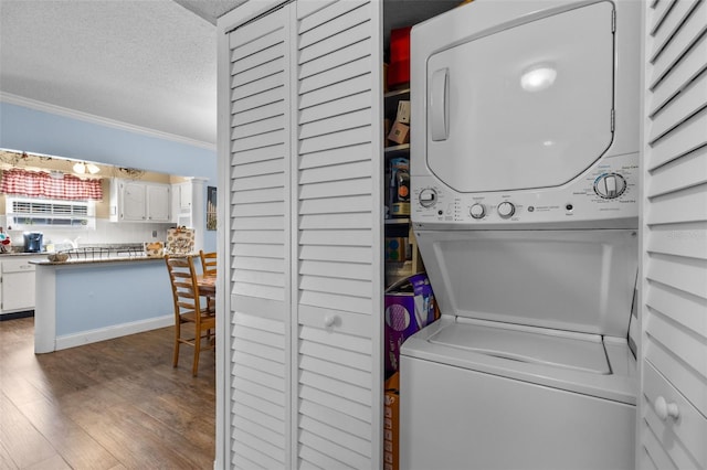 clothes washing area featuring dark hardwood / wood-style floors, a textured ceiling, stacked washer / drying machine, and ornamental molding